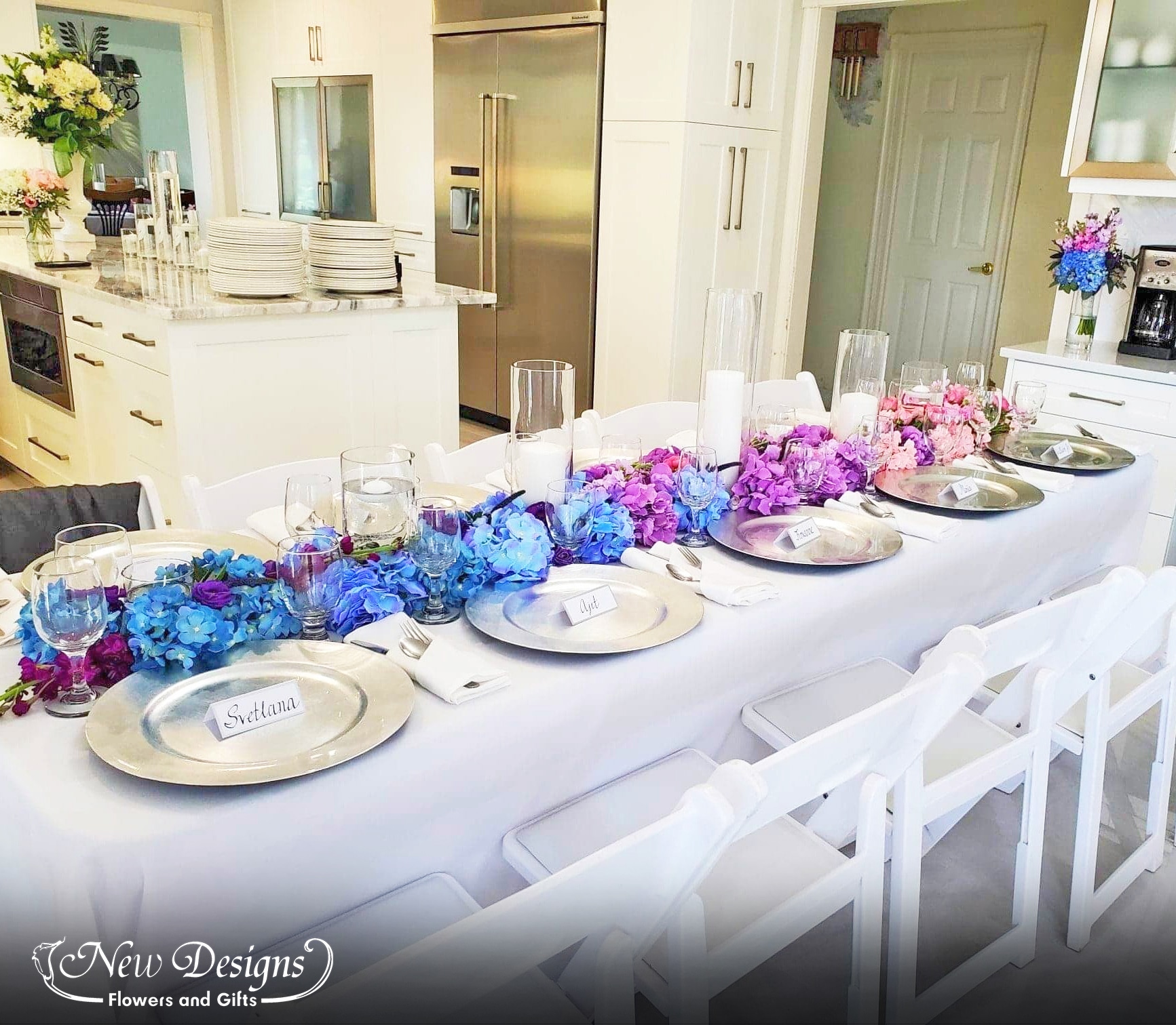 A Garland runs down the center of a crisp home table setting, of full lush hydrangeas in an ombre orientation, flowing seamlessly from Pink to Purple to Blue